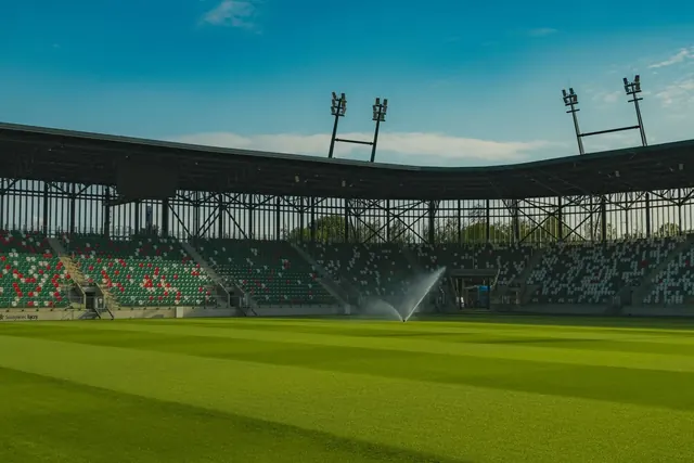 Tyhjä jalkapallostadion kirkkaan sinistä taivasta vasten