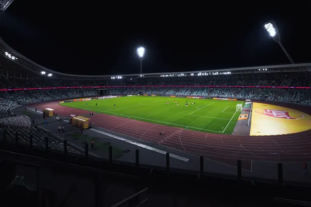 Kirkkaasti valaistu tyhjä jalkapallostadion illalla