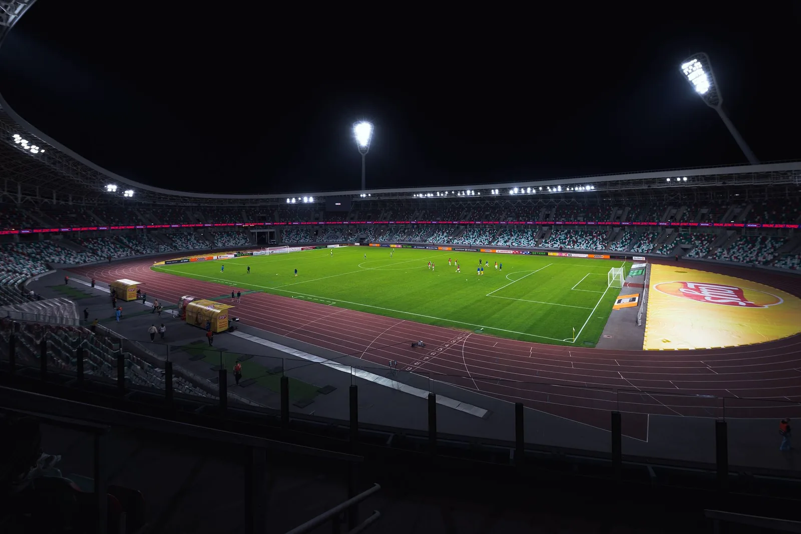 Kirkkaasti valaistu tyhjä jalkapallostadion illalla